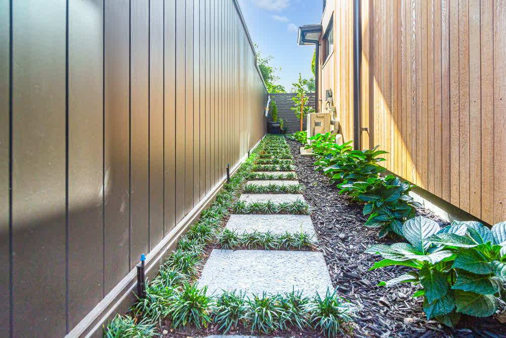 Stepping pavers down side of house through black mulch and planting
